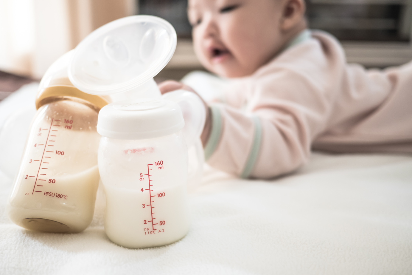 Baby Touching the Milk Bottle and Breast Pump